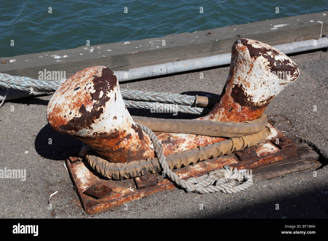 Un double dock bitt bollard montre des années d'utilisation qu'il détient toujours une aussière du cargo. Banque D'Images