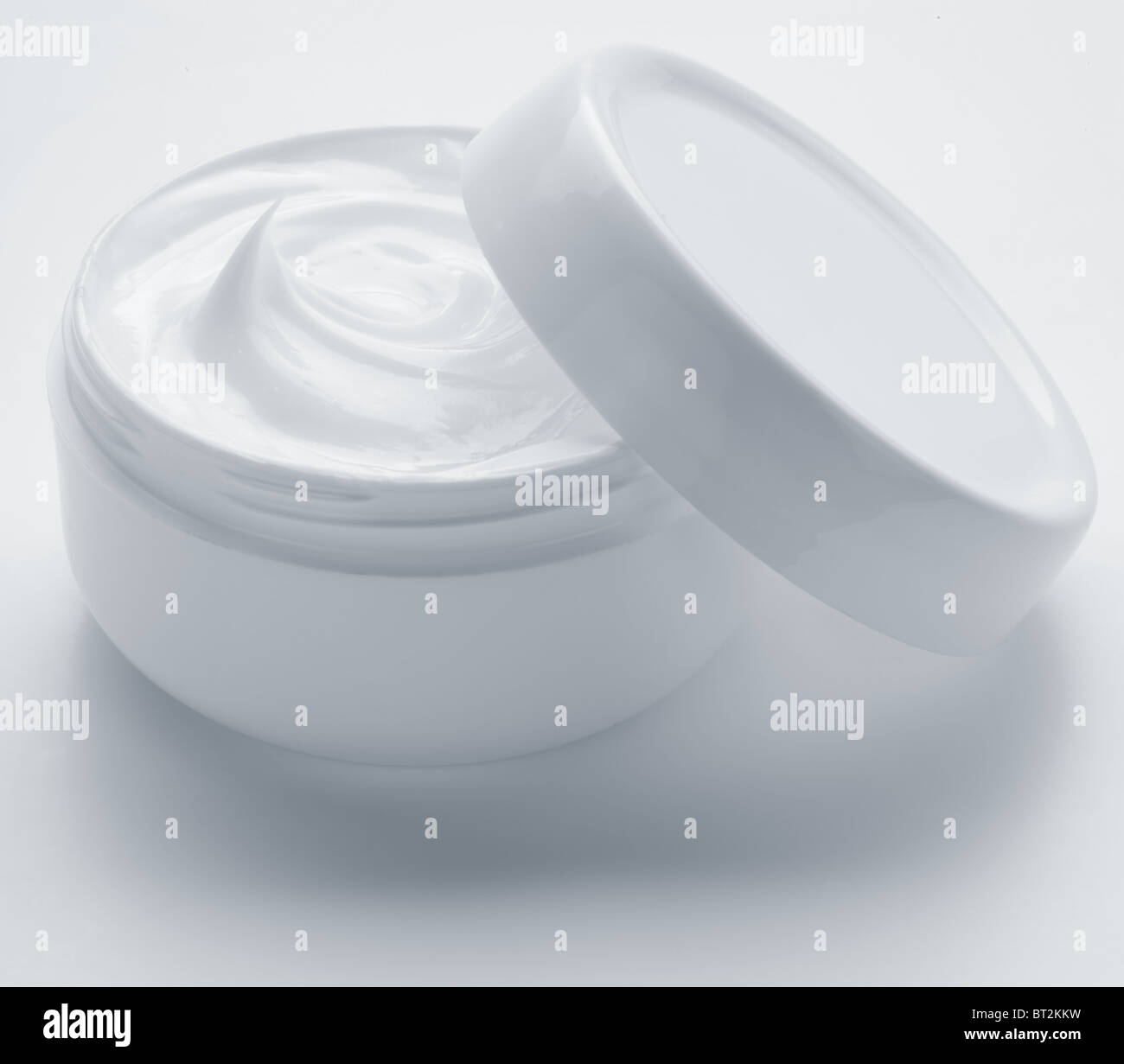 Ouvert contenant en plastique avec de la crème sur un fond blanc. Banque D'Images