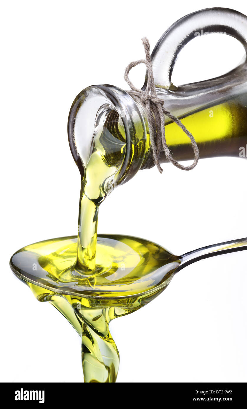 L'huile d'olive découlant de carafe dans la cuillère isolé sur fond blanc. Banque D'Images