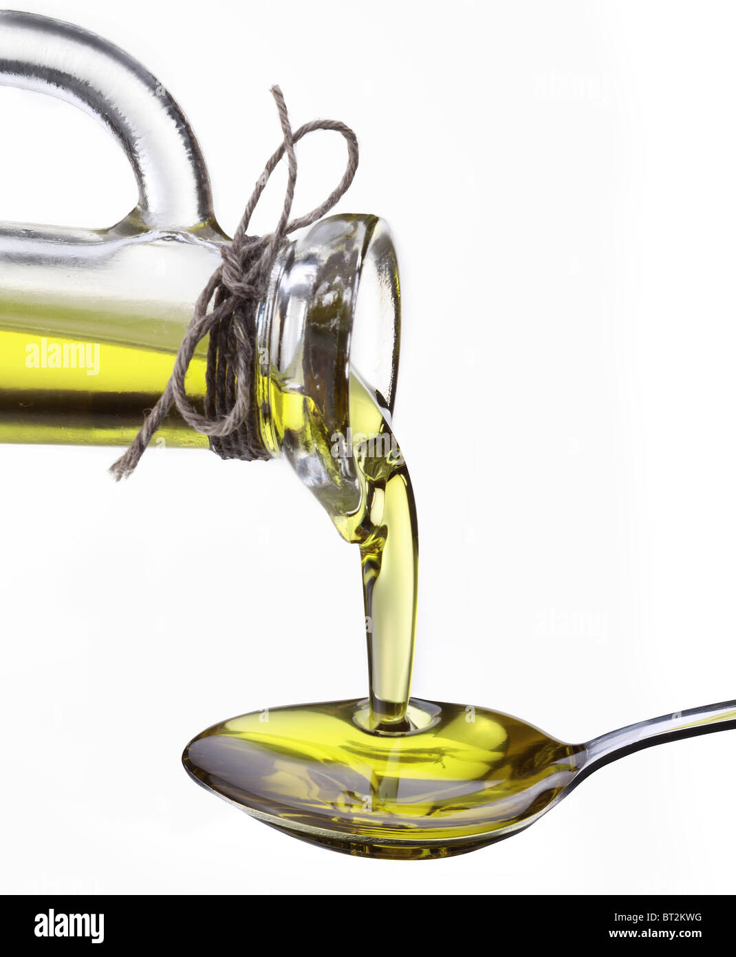 L'huile d'olive découlant de carafe dans la cuillère isolé sur fond blanc. Banque D'Images