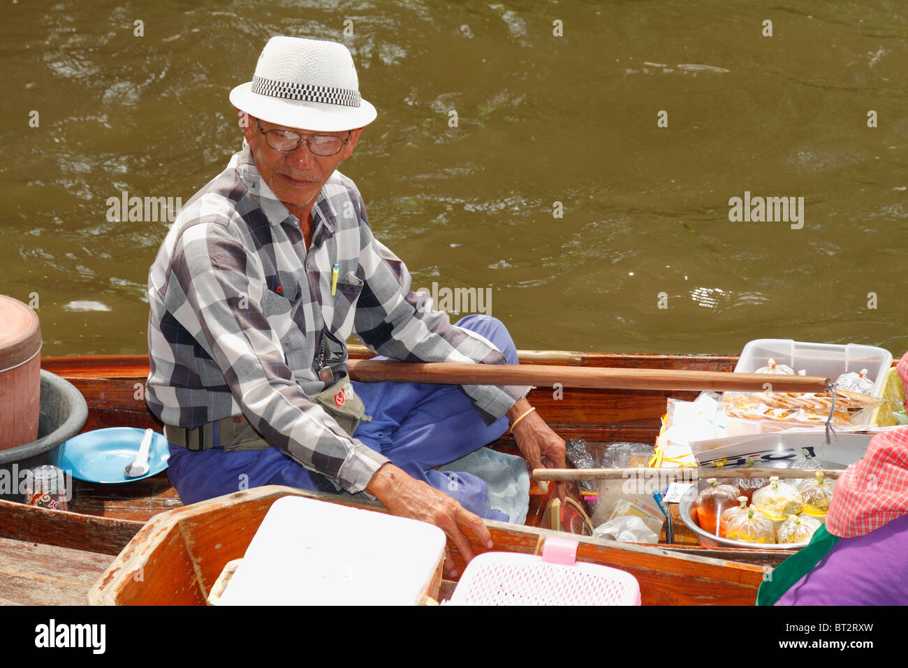 Personnes âgées Thai Man vendeur vendre de la nourriture à sa barque (barque), au Marché Flottant, Bangkok, Thaïlande, septembre 2010 Banque D'Images