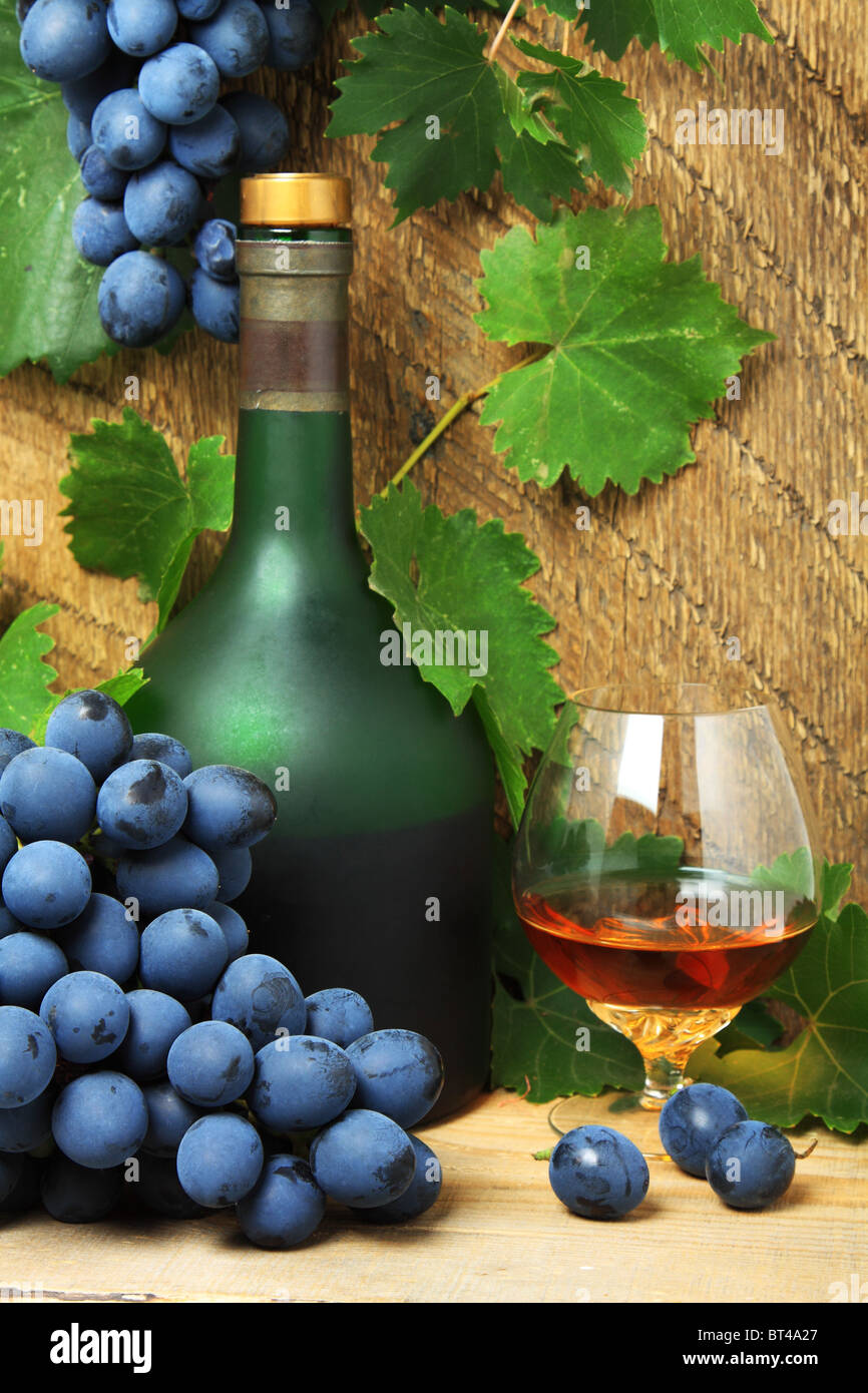 Nature morte avec bouteille, verre de cognac et grappe de raisins Banque D'Images