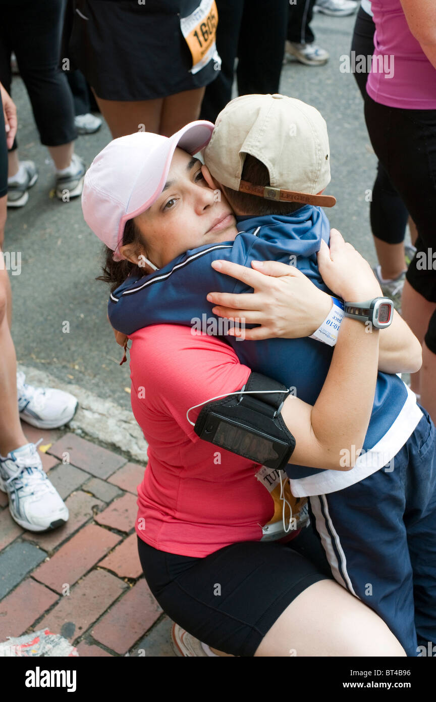 Mi Années '30 Hispanic Woman reçoit un câlin de son fils de 5 ans après une course sur route. La Tufts 10k pour les femmes à Boston MA. Banque D'Images