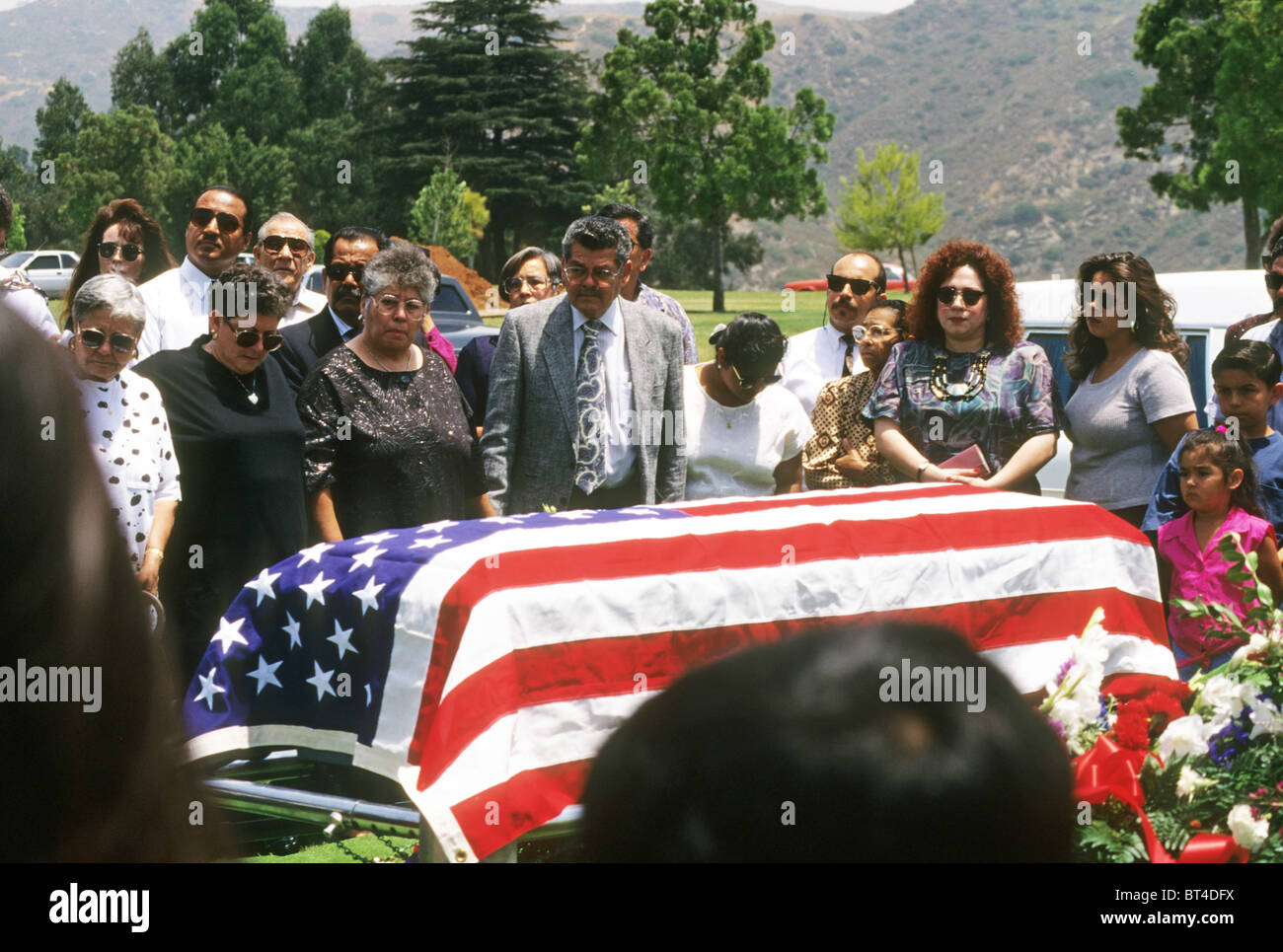 Funérailles cimetière enterrement famille hispanique rite cérémonie mort mourir triste chagrin pleurer pleurer amour cercueil drapé d'un drapeau Banque D'Images