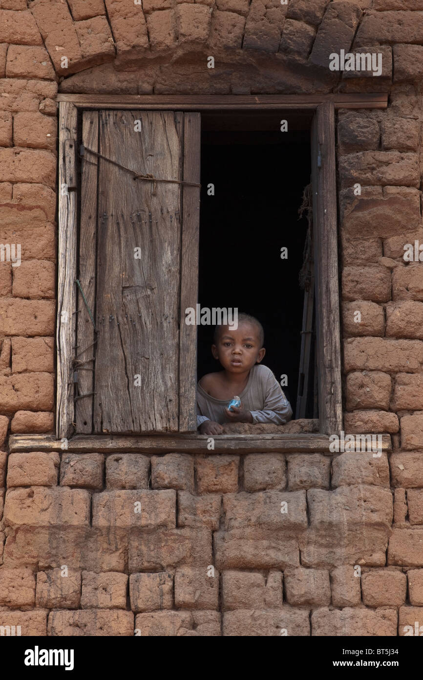 Jeune garçon à la fenêtre de sortie, Antananarivo, Madagascar. Banque D'Images