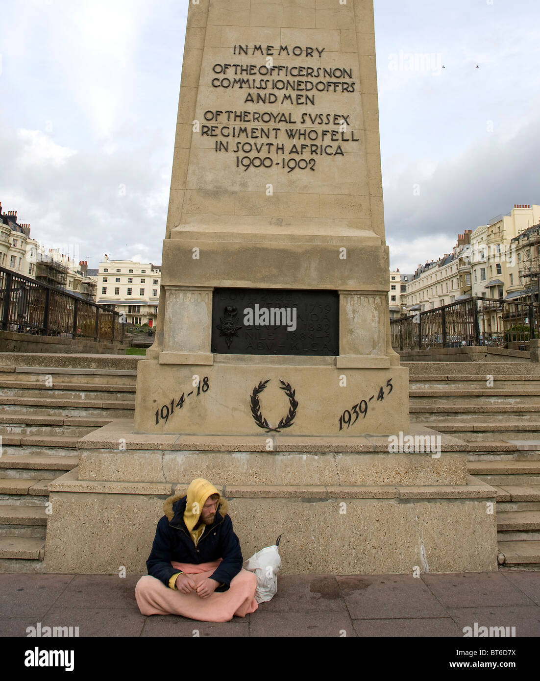 Un mendiant par un monument commémoratif de guerre Banque D'Images