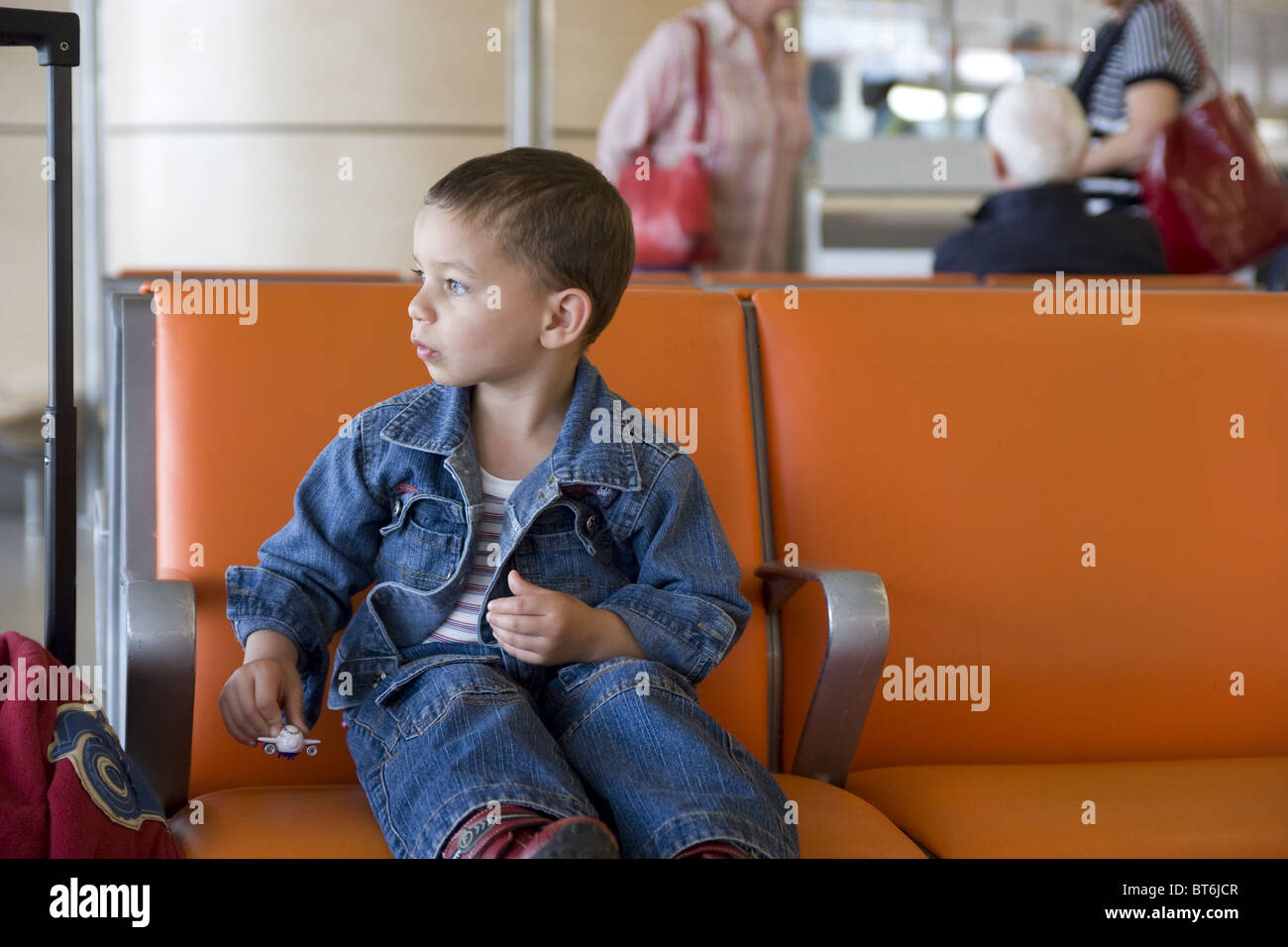 Petit garçon assis seul dans la salle d'embarquement de l'aéroport Banque D'Images