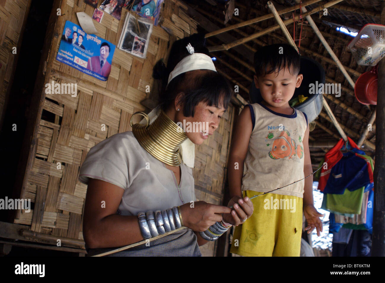 Un Paduang de réfugiés Karen baidjan mère fait un jouet pour son fils au camp de réfugiés de leur maison à Ban Nai Soi, en Thaïlande. Banque D'Images