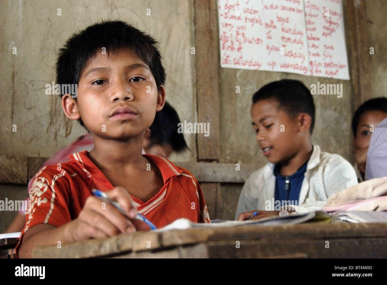 Un garçon de 9 ans est assis à un bureau étude de langue à l'école primaire de Parti communiste du Laos. Banque D'Images