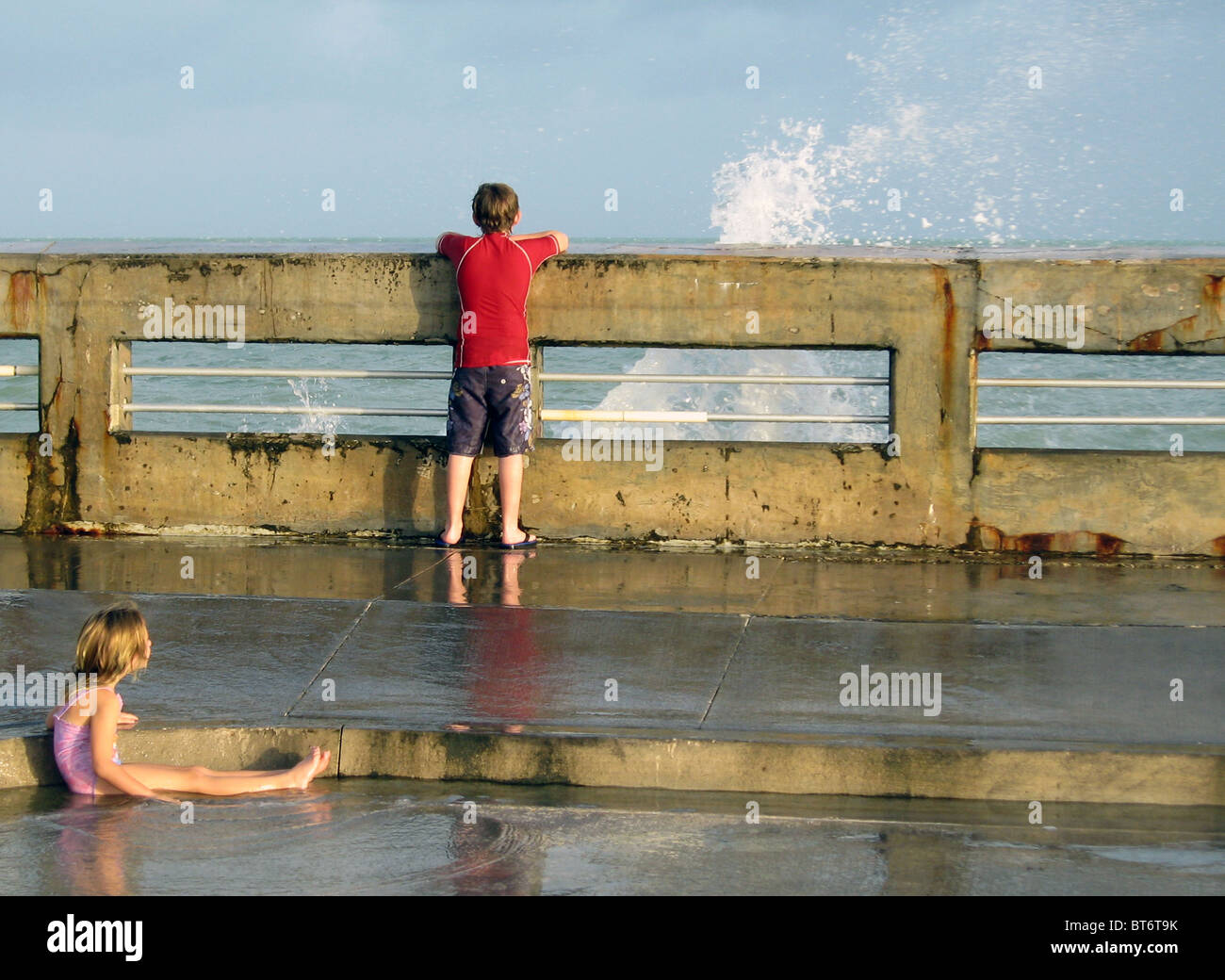 Un garçon et une fille sur un quai, avec des projections d'eau, rappelant une peinture de Norman Rockwell. Banque D'Images