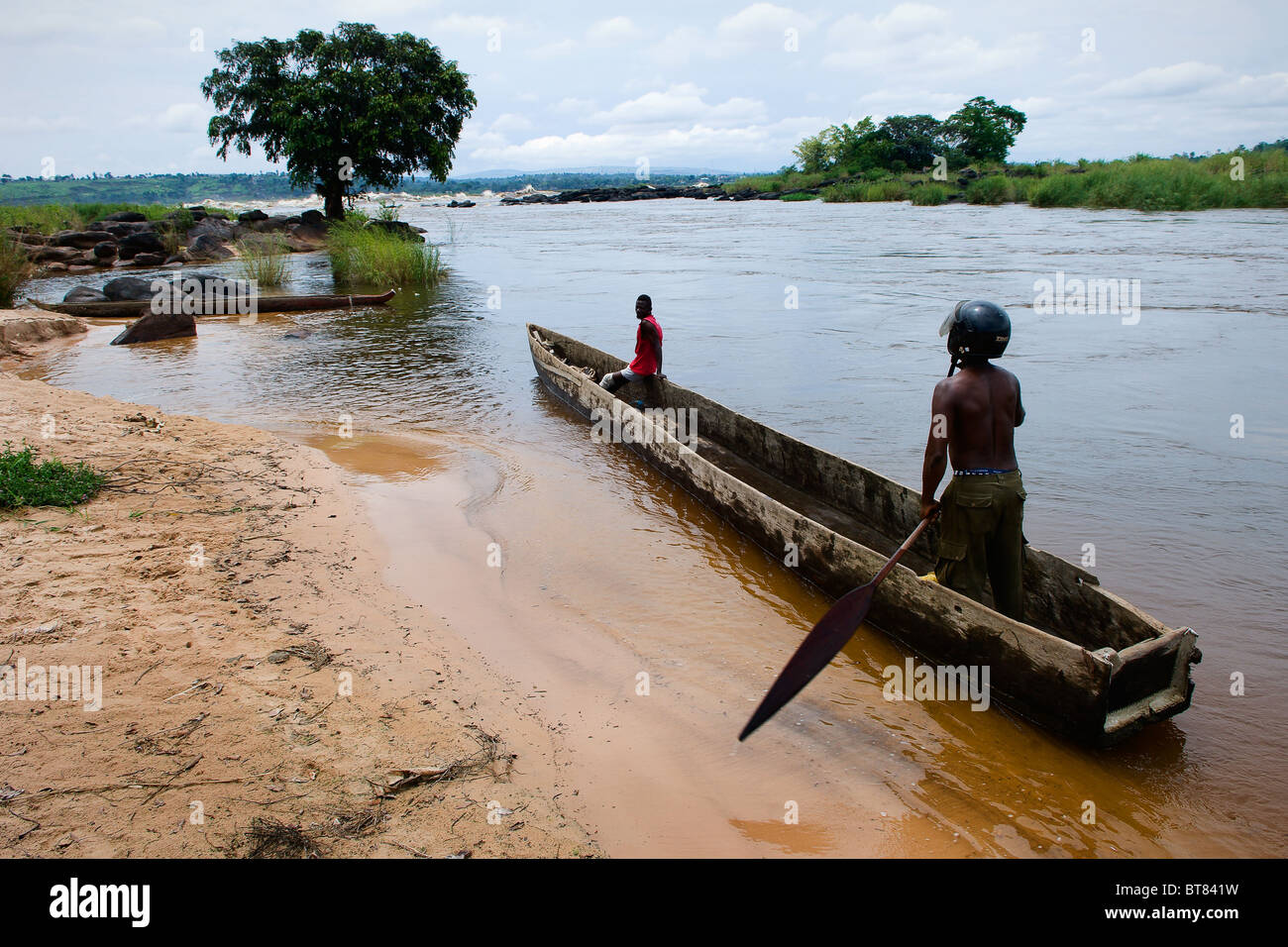 Deux hommes flottent dans un bateau en bois sur le fleuve Congo Banque D'Images