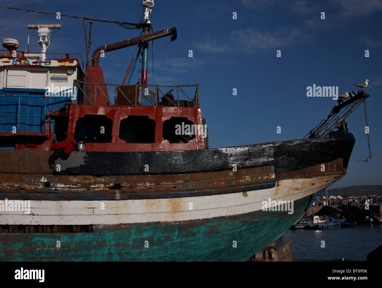 Une nouvelle couche de peinture est appliquée sur ce bateau de pêche à Essaouira, Maroc Banque D'Images