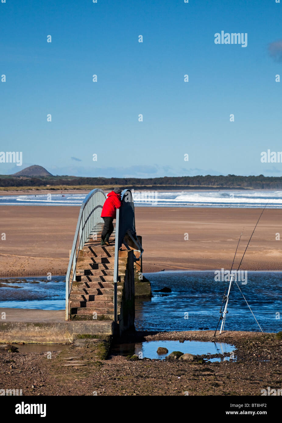 L'homme à la veste rouge Belhaven pêche Beach, East Lothian en Écosse, Royaume-Uni, Europe Banque D'Images