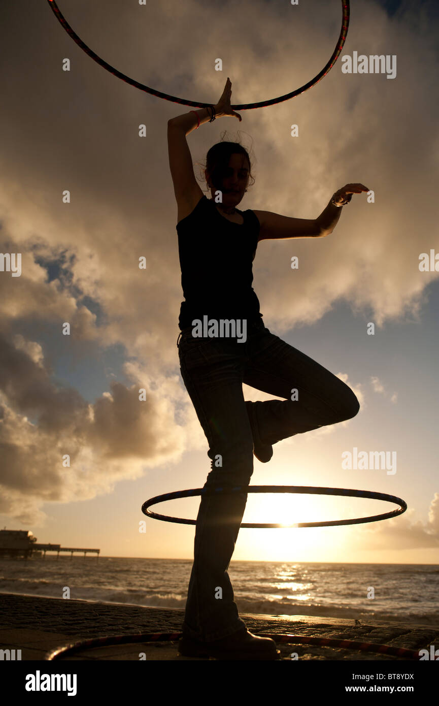 Une jeune femme étudiant à l'université d'Aberystwyth en utilisant hoolah hula hoops au coucher du soleil, UK Banque D'Images