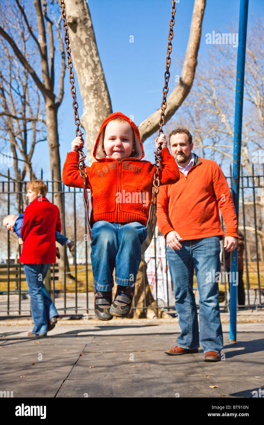 Garçon sur une balançoire dans Battery Park, Manhattan, New York City (la mère, le père et les deux enfants de la même famille) Banque D'Images