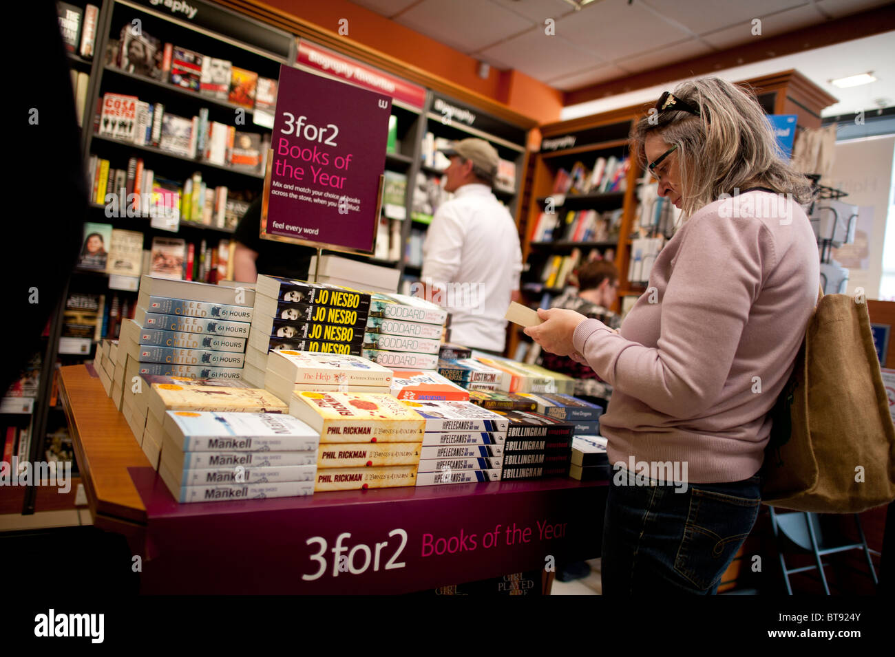 Une femme parcourt 3 pour 2 offre des livres en librairie Waterstones UK Banque D'Images