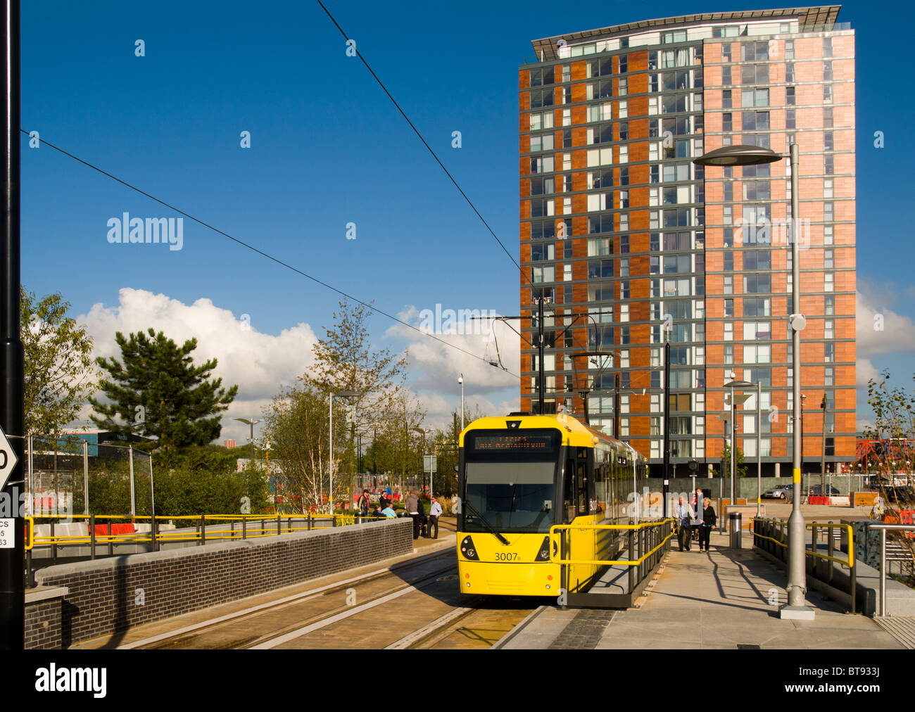 Un approacing MediaCityUK tram Metrolink, Salford Quays, Manchester, Angleterre, Royaume-Uni. Derrière se trouve la ville d'appartements lofts. Banque D'Images