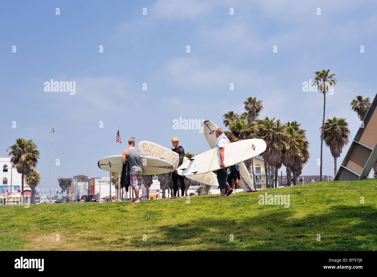 Groupe de surfers de quitter la plage transportant des planches, Venice Beach, Los Angeles, Californie, États-Unis. À la caméra de Banque D'Images