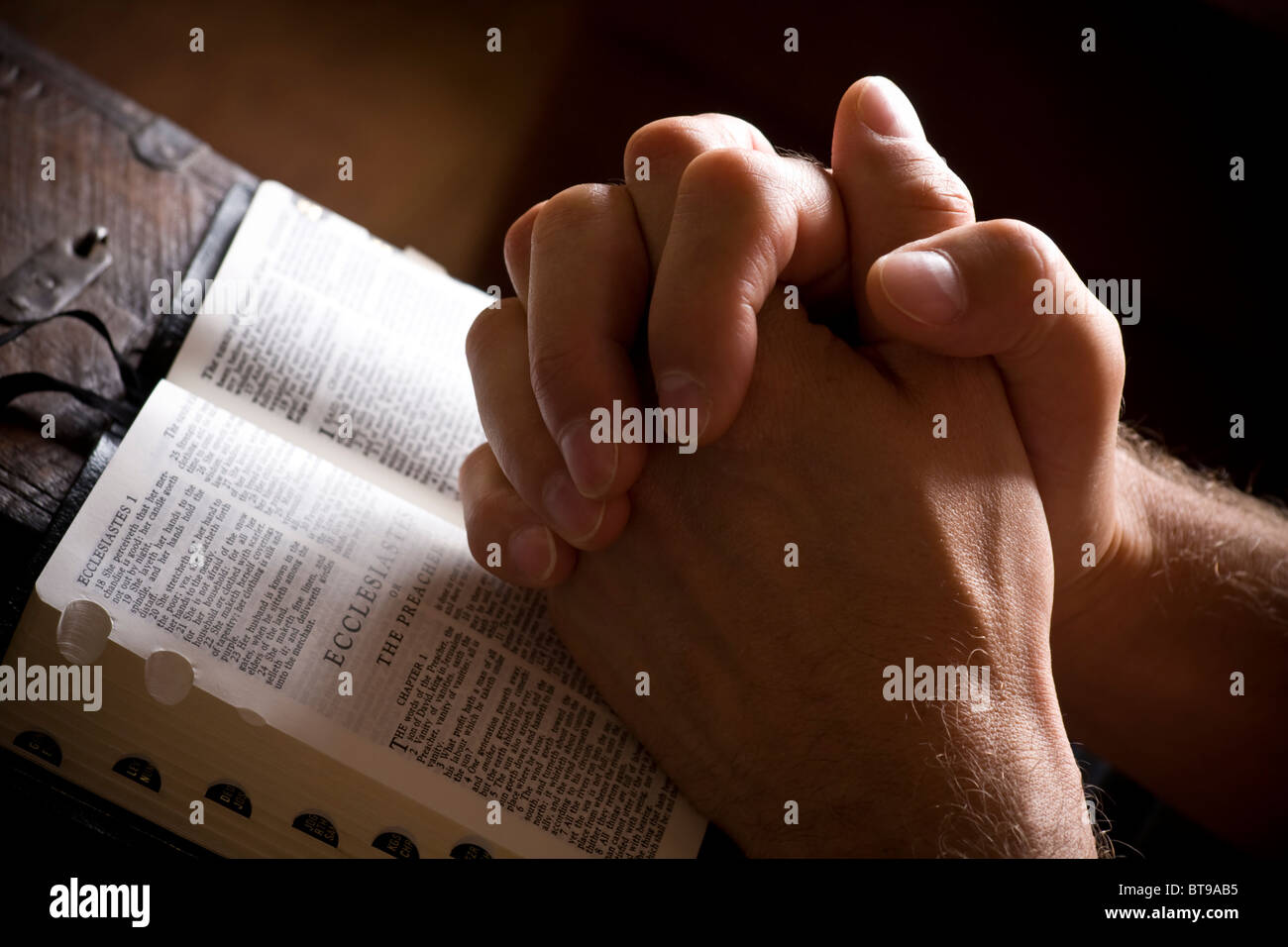 Priant les mains sur une bible ouverte Banque D'Images
