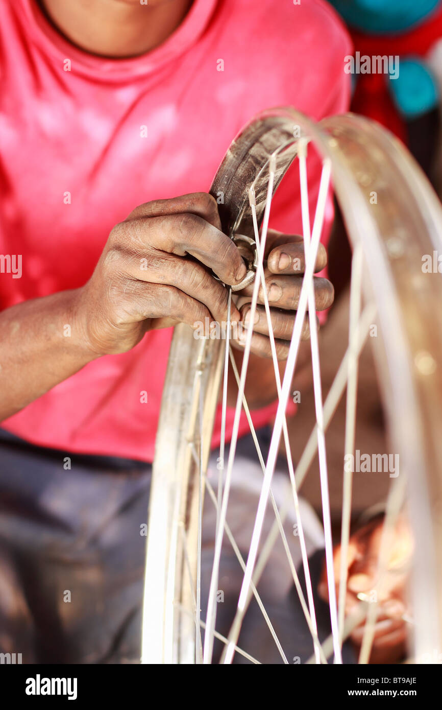Afrique Malawi Mécanicien Vélo roue fixation rayons d'une bicyclette. Close up. Orientation verticale, couleur, l'accent peu profondes. Banque D'Images