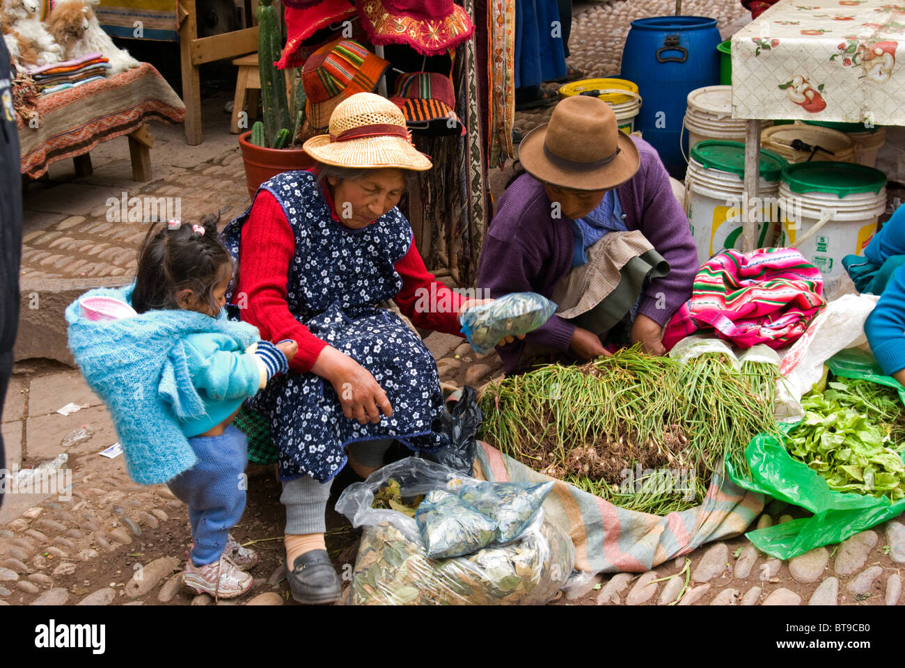 Le Pérou, la Vallée Sacrée, Pisac, marché du dimanche, petite fille aide les grands-mères préparent leurs verts pour la vente. Banque D'Images