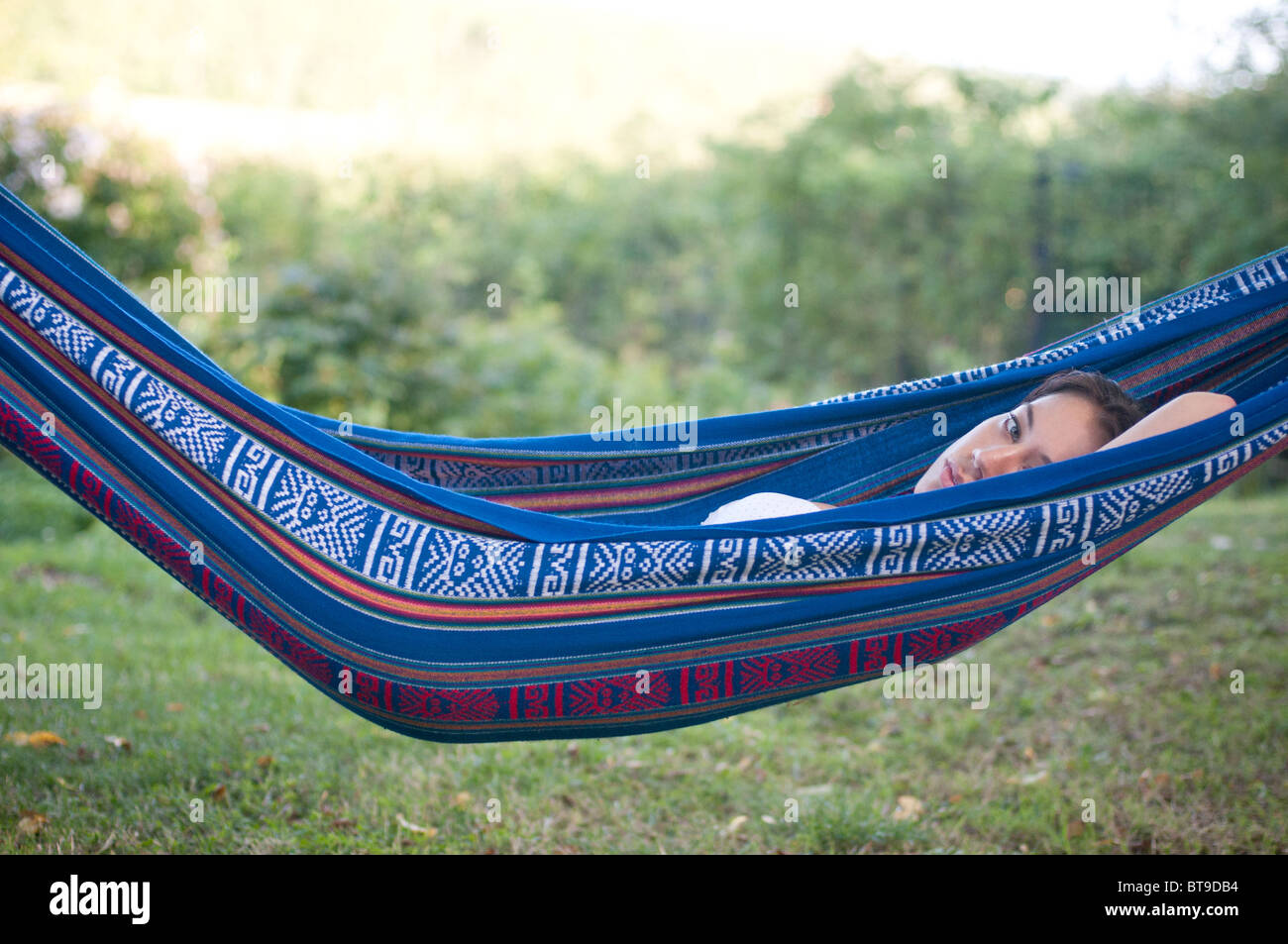 Une jeune femme couchée dans un hamac dans un jardin Banque D'Images