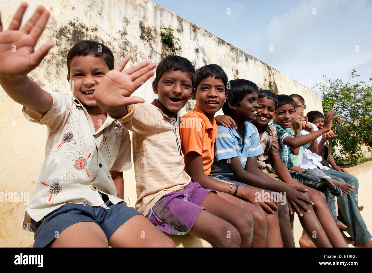 Village de l'Inde rurale garçons assis sur un mur d'école forme en plein soleil. L'Andhra Pradesh, Inde Banque D'Images