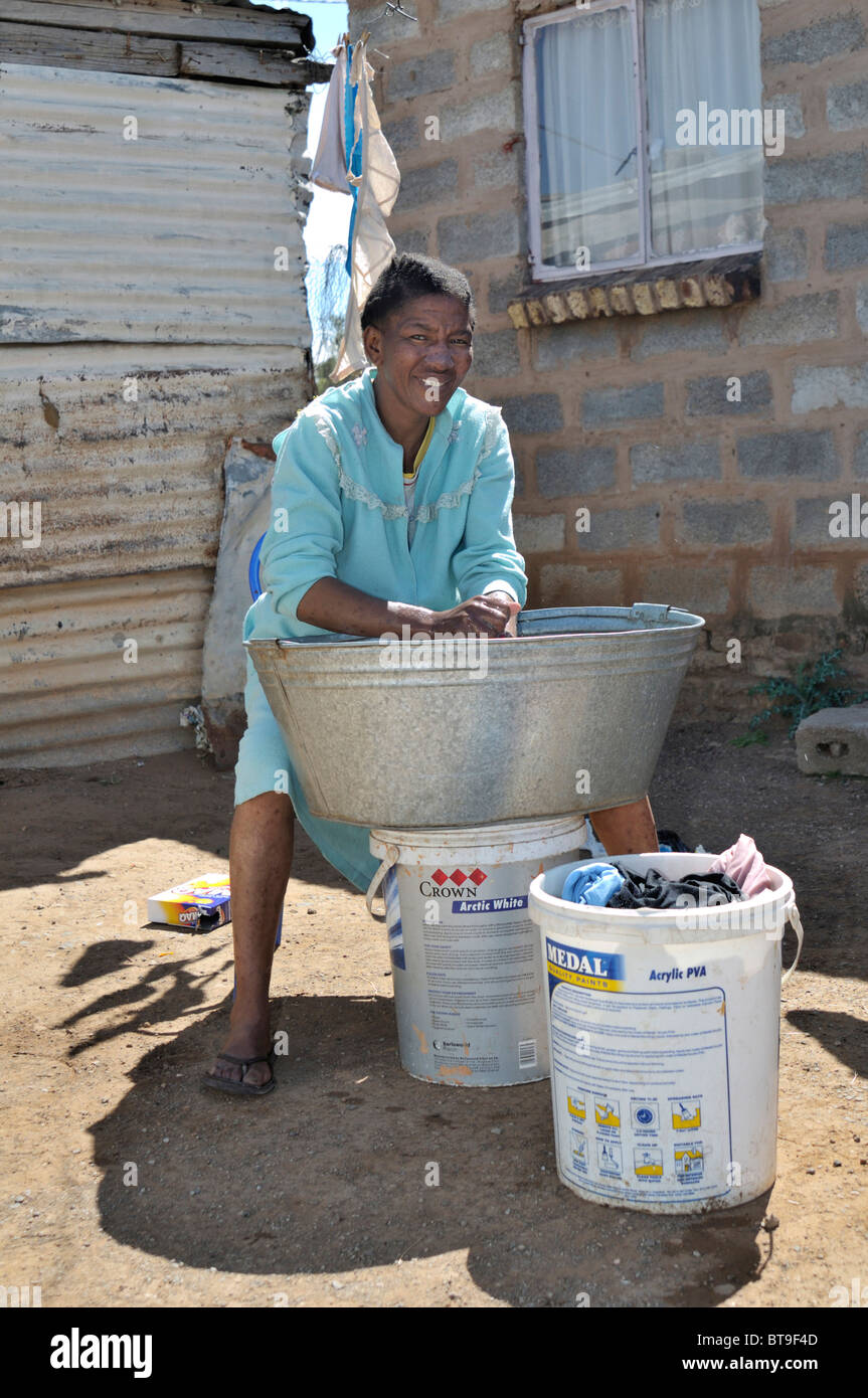 Les femmes lavent les vêtements dans un bain d'étain en face de la maison, des bidonvilles, canton, Queenstown, Eastern Cape, Afrique du Sud, l'Afrique Banque D'Images