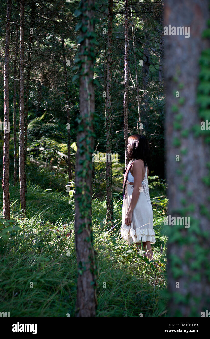Une jeune femme dans une forêt de pins, vêtue d'une robe blanche Banque D'Images