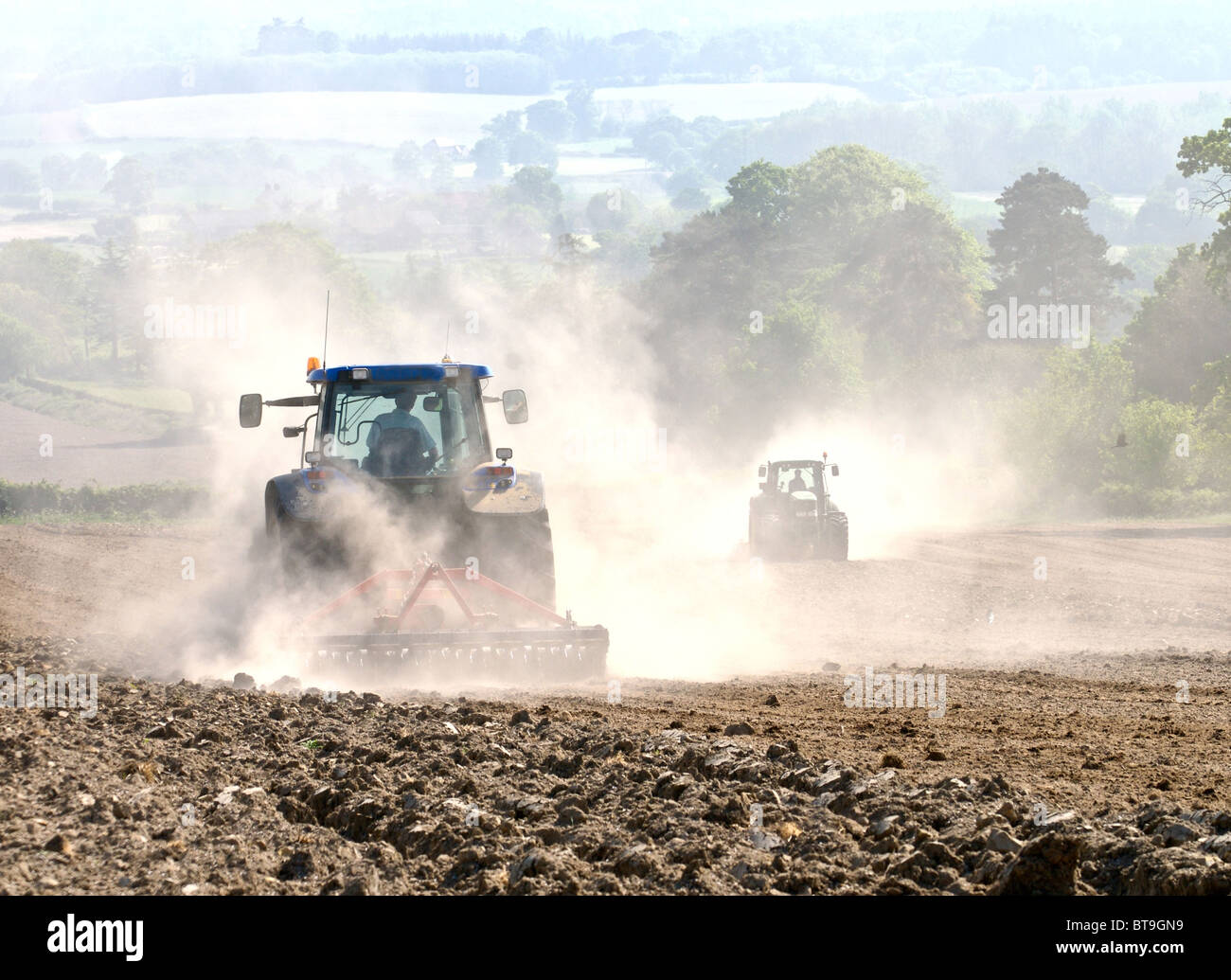 Tracteur travaillant sur des terres sèches dans le Sussex pulvériser le sol et créer des nuages de poussières qui est soufflée dans le vent. Banque D'Images