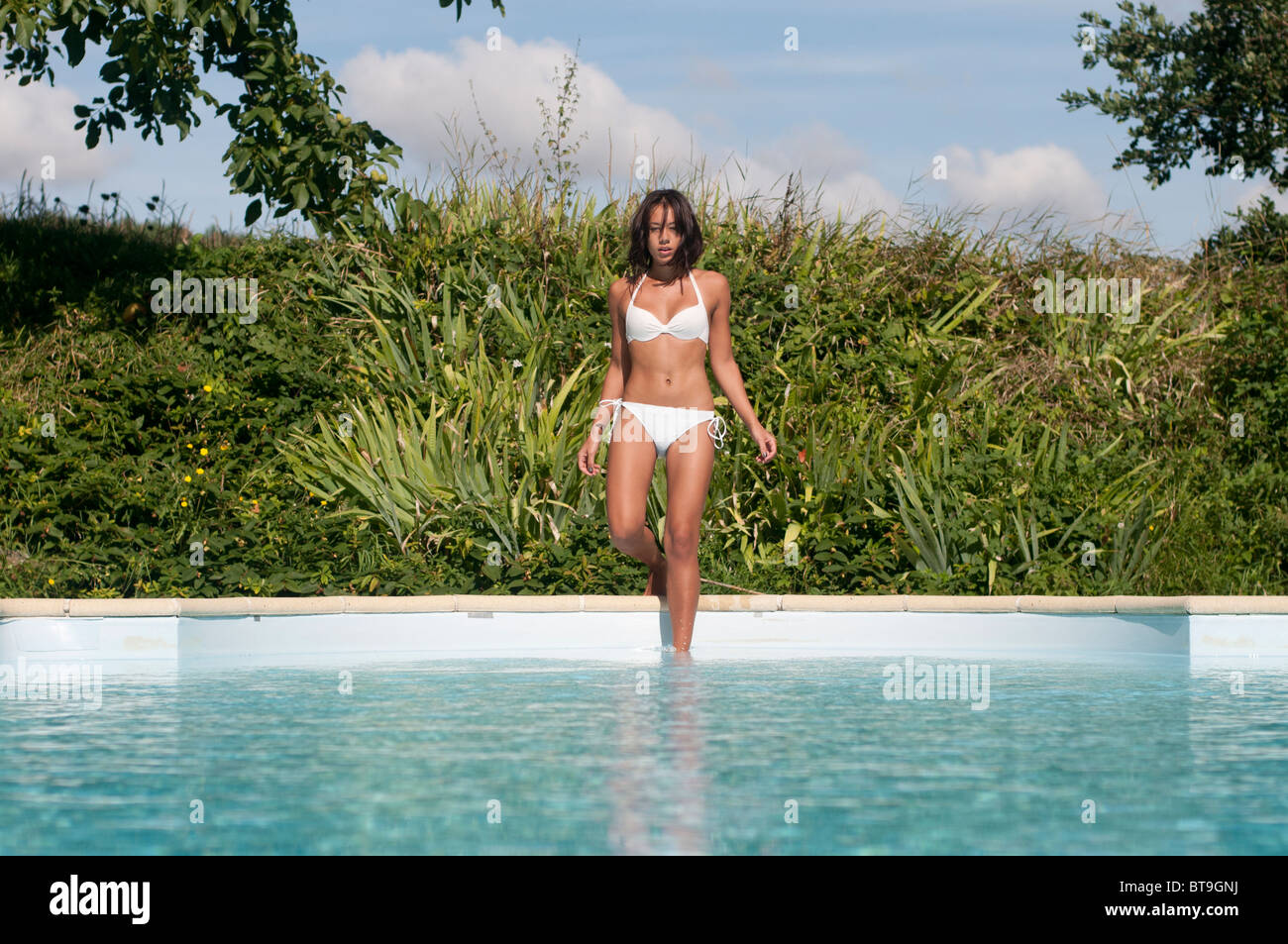 Une femme marchant dans une piscine extérieure Banque D'Images