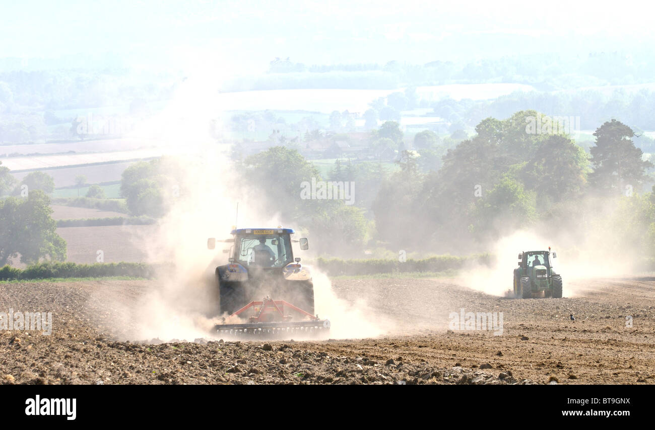 Tracteur travaillant sur des terres sèches dans le Sussex pulvériser le sol et créer des nuages de poussières qui est soufflée dans le vent. Banque D'Images