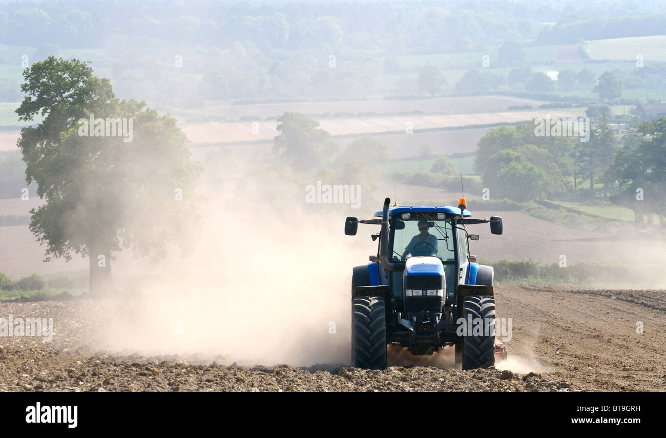 Tracteur travaillant sur des terres sèches dans le Sussex pulvériser le sol et créer des nuages de poussières qui est soufflée dans le vent. Banque D'Images