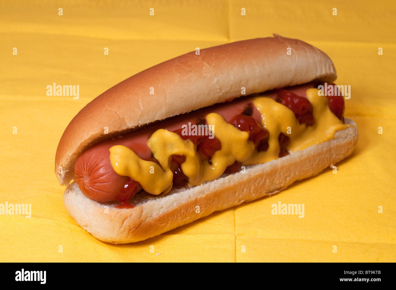 Hot-dog avec du ketchup et de la moutarde sur serviette jaune. Banque D'Images