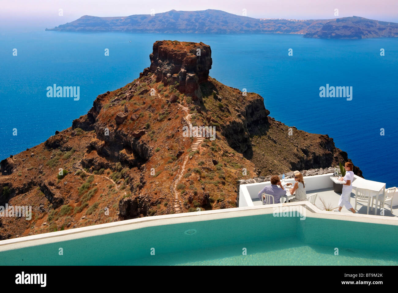 Les touristes sur une terrasse de l'hôtel donnant sur le bouchon volcanique d'Imerovigli, Santorini, Grèce. Banque D'Images
