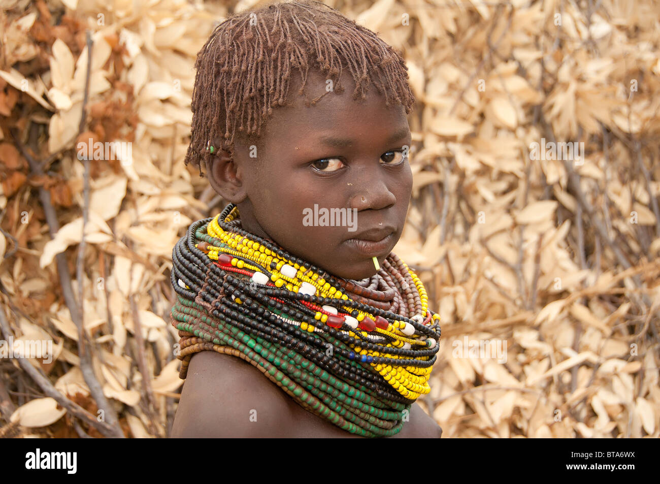 Les Nyangatom (Bumi) fille avec des tas de perles en face de sa hutte, vallée de la rivière Omo, en Ethiopie Banque D'Images