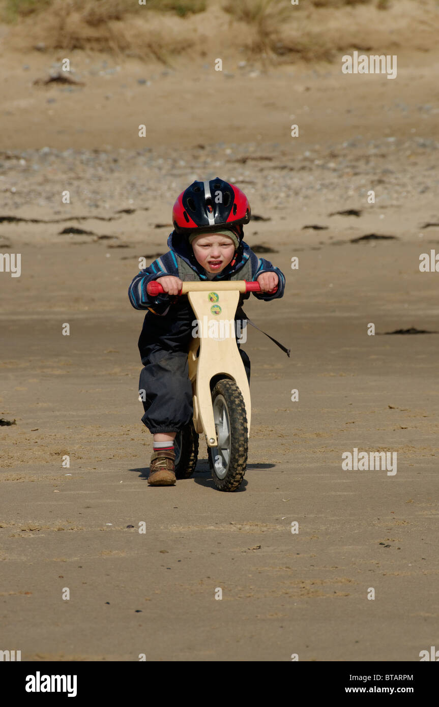 Un garçon à cheval un équilibre à vélo, plage Newborough Anglesey. Banque D'Images