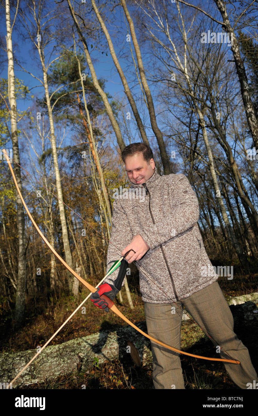 Homme de tir avec arc et flèche en forêt, Stockholms Lan, Suède Banque D'Images