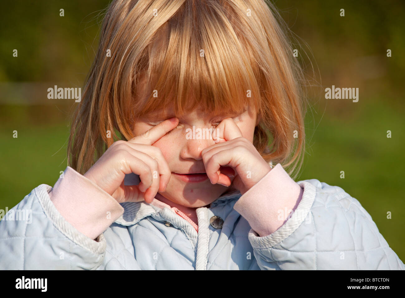 Portrait d'une petite fille frottant ses yeux Banque D'Images