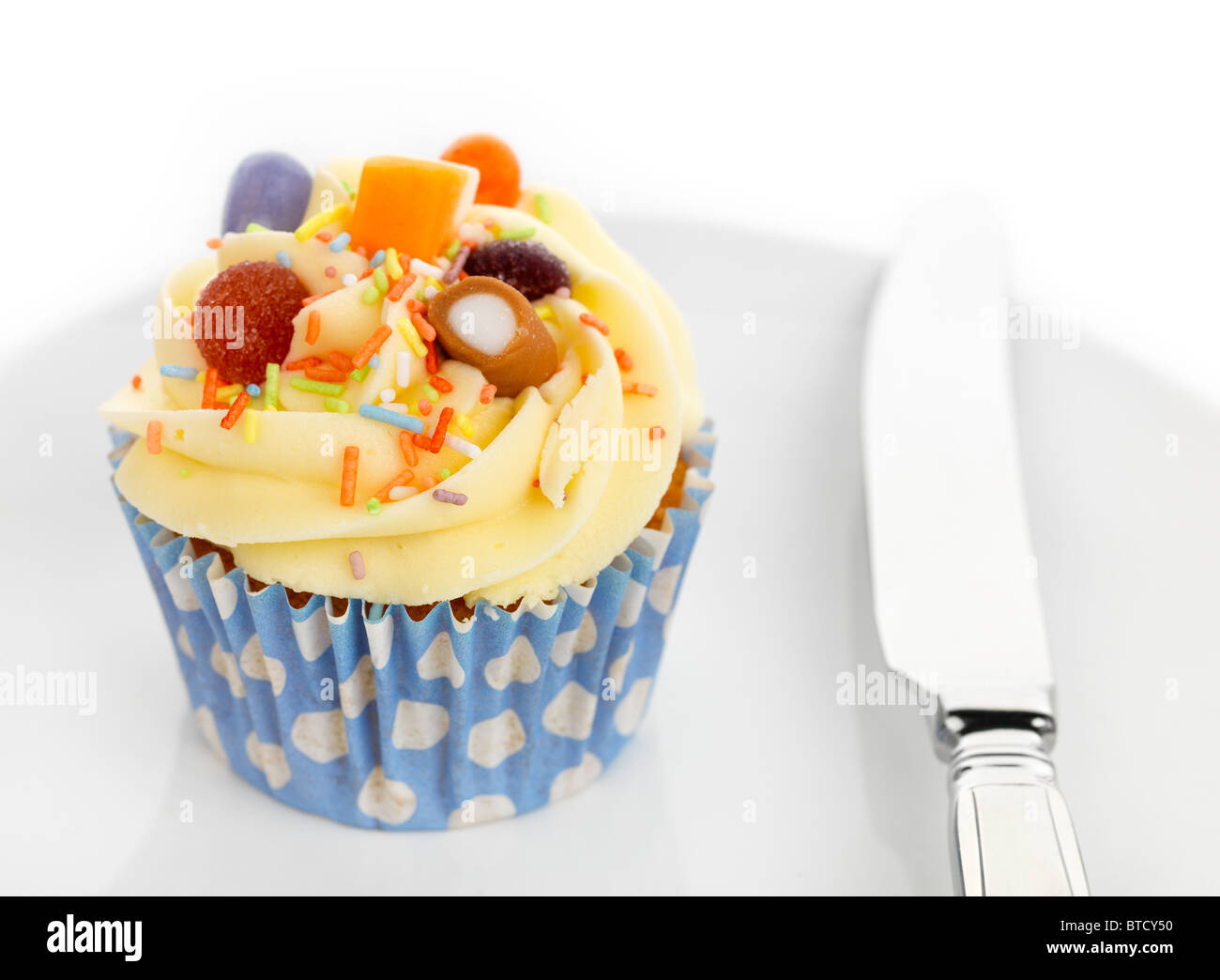 Candy cupcake, un petit gâteau et le couteau sur une plaque blanche avec des bonbons décorer le buttercream topping Banque D'Images