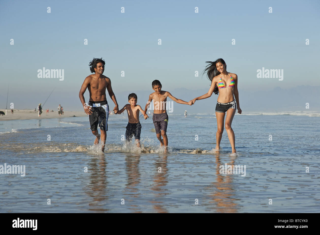 La famille indienne, habillés en maillot de bain, jouant dans les vagues. Banque D'Images