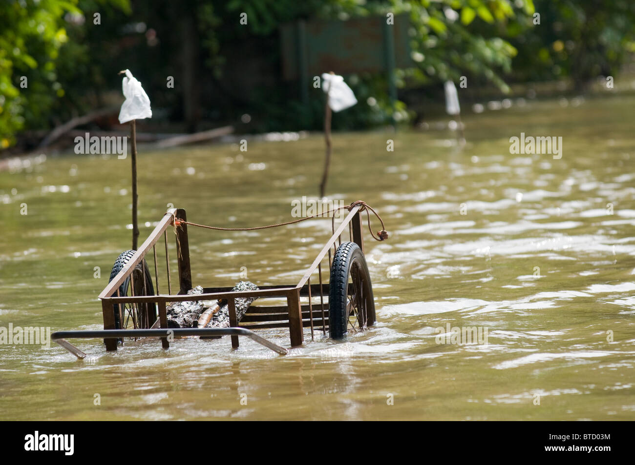 Charrette à gauche sur une route inondée dans les régions rurales de la Thaïlande durant la saison de la mousson. Banque D'Images