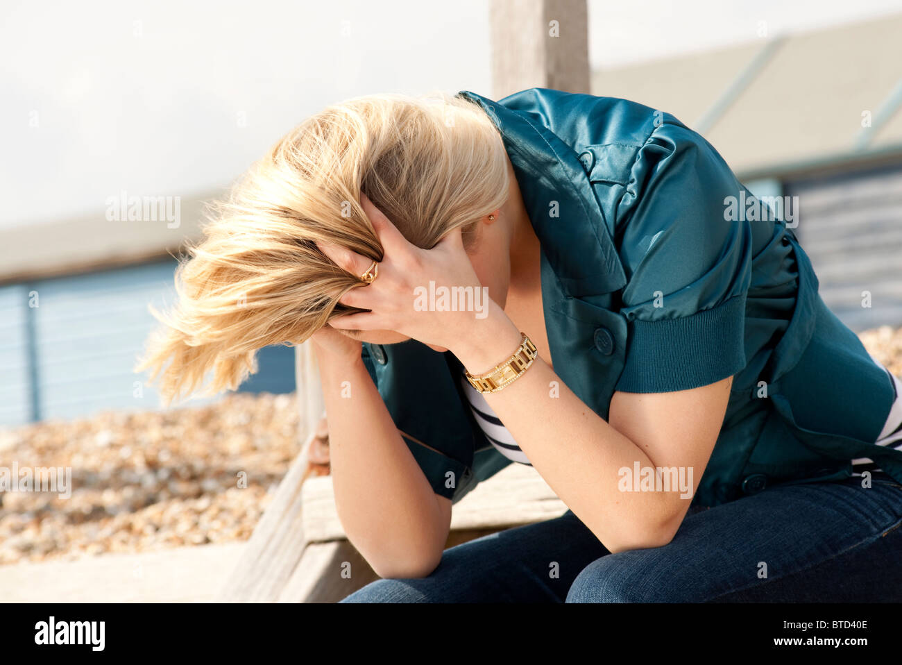 Femme blonde head in hands Banque D'Images