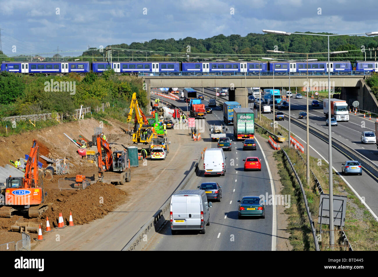 Infrastructure de transport train de passagers sur le pont ferroviaire au-dessus de la route travaux de contraste élargissement de l'autoroute M25 sortie 28 Brentwood Essex Angleterre Royaume-Uni Banque D'Images