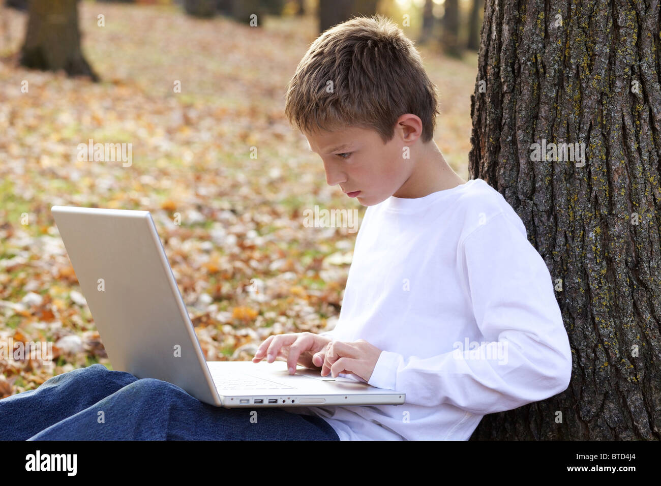 Jeune garçon en utilisant un ordinateur portable outdoor Banque D'Images