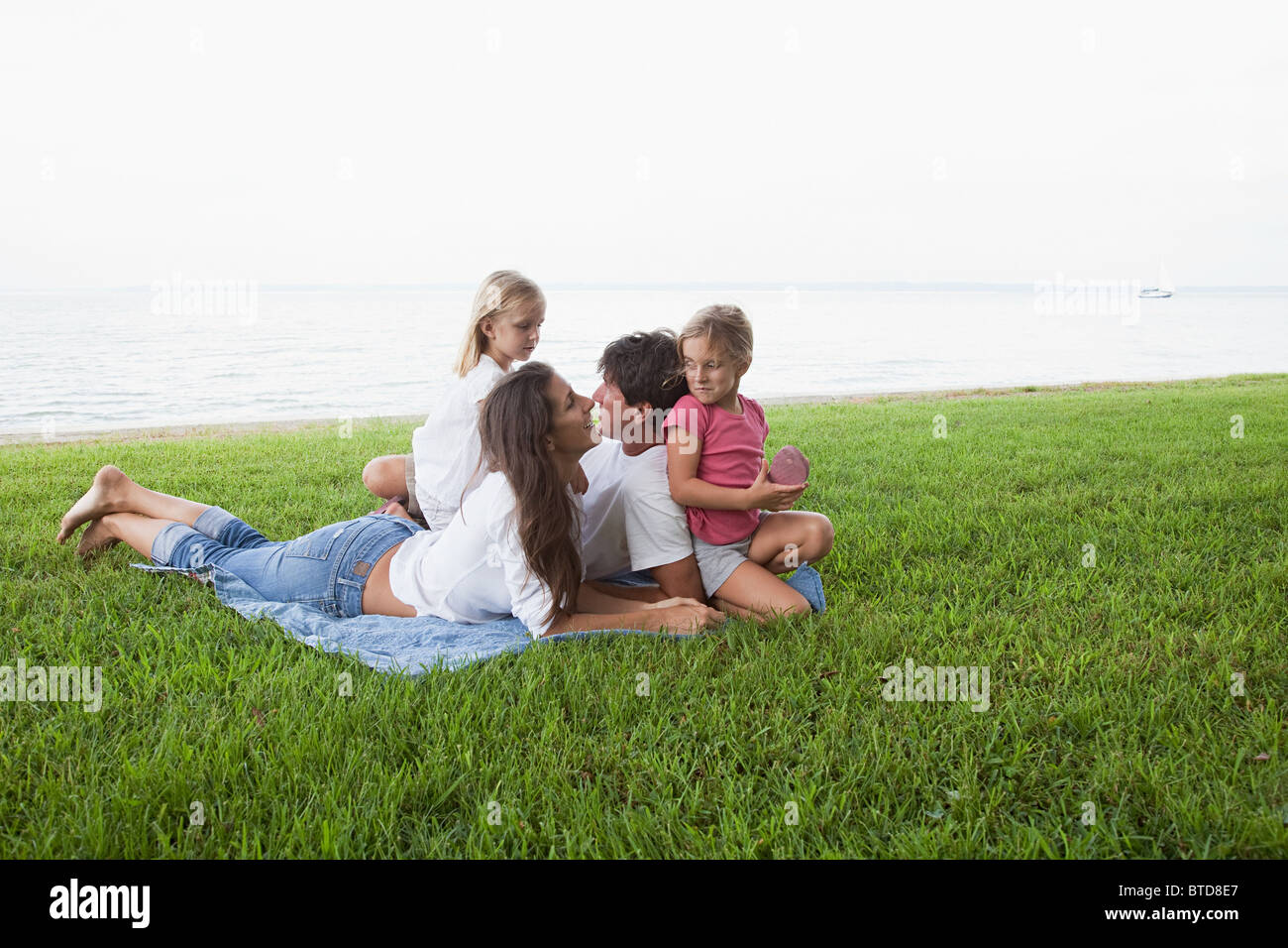 Family relaxing on grass par la mer Banque D'Images