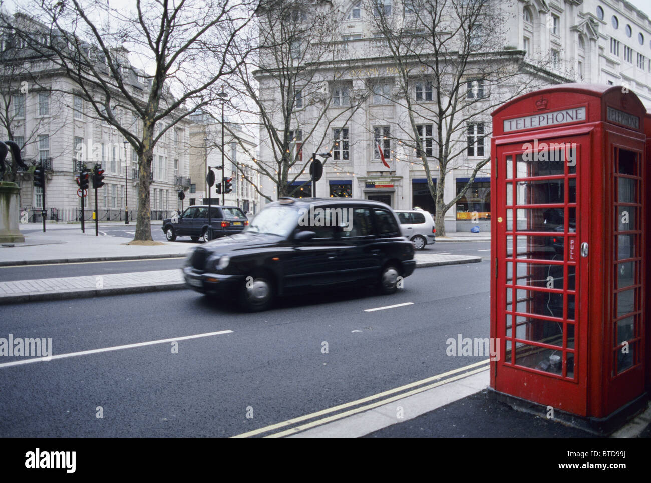 Black taxi cab driving passé un téléphone rouge fort, Londres, Angleterre Banque D'Images