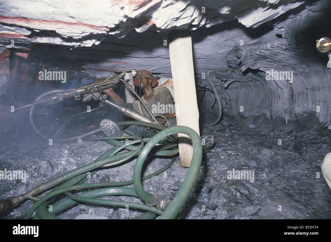 Le forage sous terre dans une mine d'montrant les flexibles haute pression et des conditions de travail exiguës. Banque D'Images