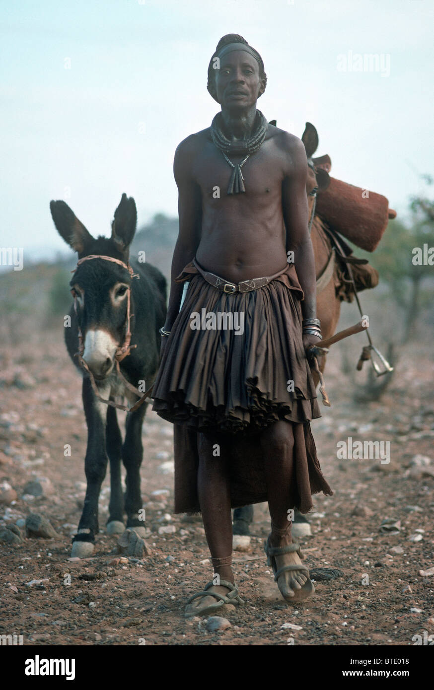 Himba homme vêtu de vêtements traditionnels conduisant un cheval et âne Banque D'Images