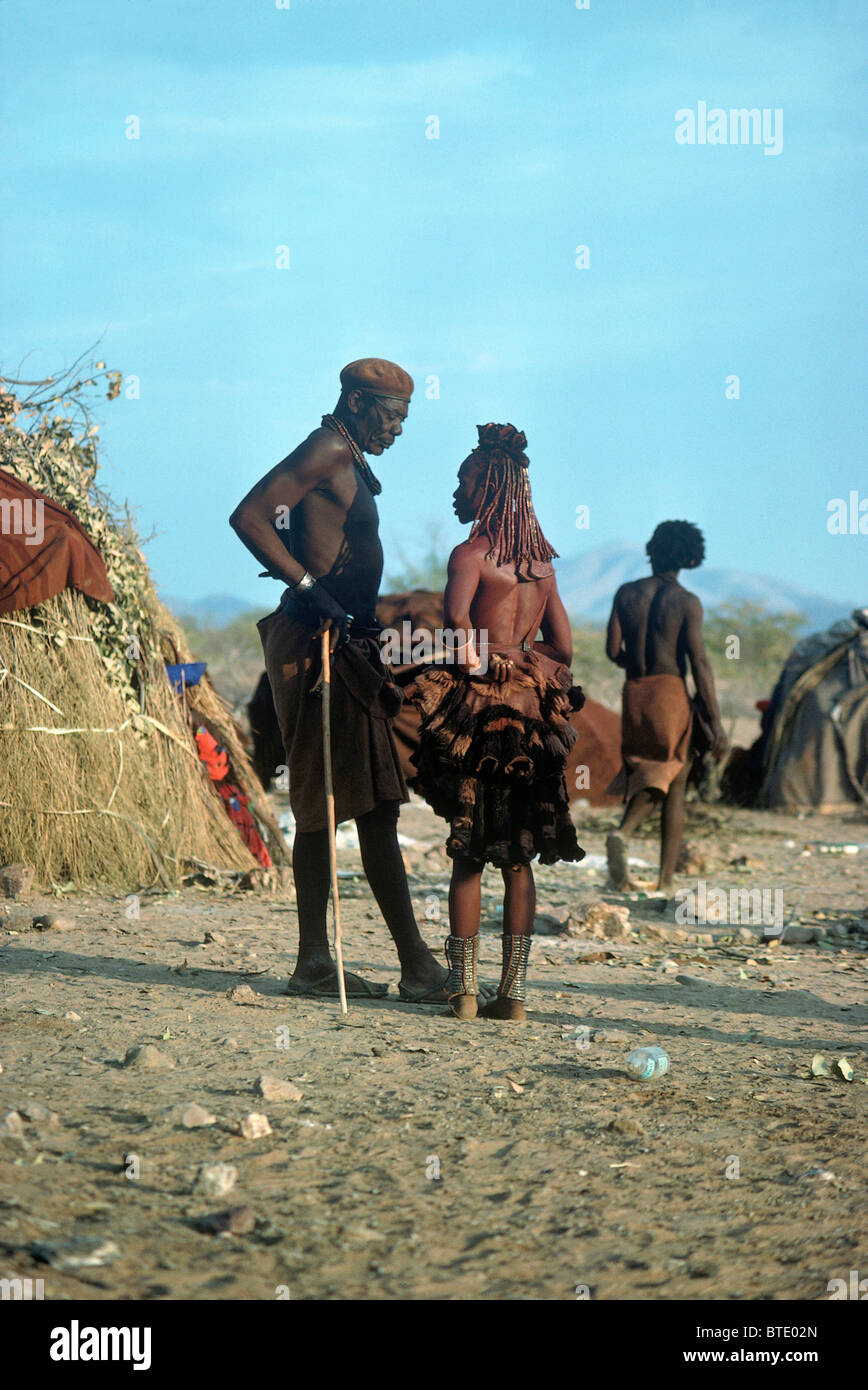 Un homme et une femme Himba converser à leur homestead Banque D'Images